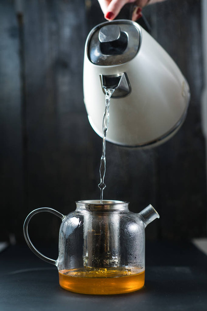 The girl pours water into the teapot. - Zdjęcie, obraz