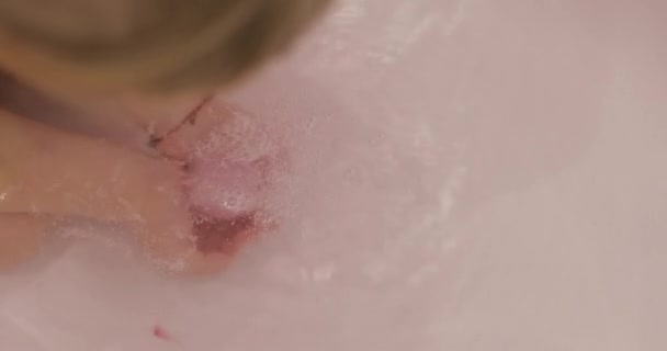 Hands of little girl puts bath bomb to the water. Ball of bath salt dissolves - Footage, Video
