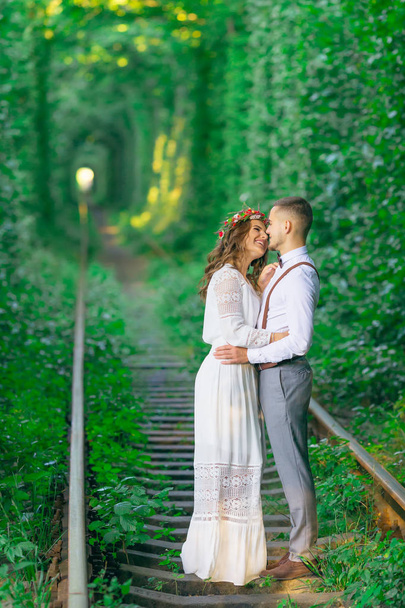 couple en vêtements de fête câlins sur le chemin de fer. les arbres forment
 - Photo, image