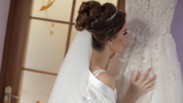Beautiful and lovely bride in night gown stands near wedding dress. Wedding - Footage, Video