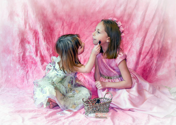 Uma menina pequena coloca compõem em sua irmã mais velha como eles jogam vestir-se
 - Foto, Imagem