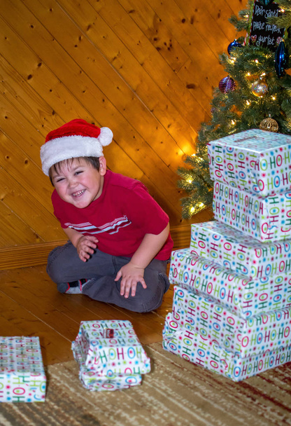 хлопчик сміється зі стопки різдвяних подарунків
 - Фото, зображення
