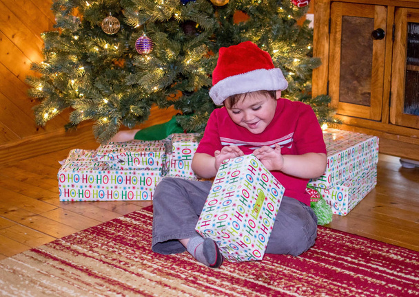 Junge öffnet ein Weihnachtsgeschenk - Foto, Bild
