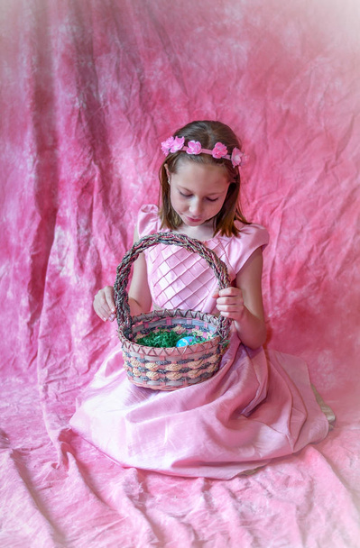 graziosa piccola gilr nel suo abito rosa pasqua posa con un cesto pasquale pastello
 - Foto, immagini