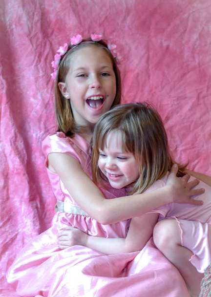 sisters laugh and hug each other in this sweet portrait - Photo, Image