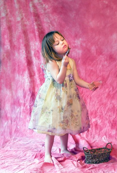 Kleines Mädchen in schickem Kleid sprüht Parfüm auf sich - Foto, Bild