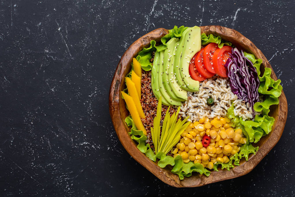 Gezonde Vegan etensbak met quinoa, wilde rijst, kikkererwten, tomaten, avocado, greens, kool, sla op zwarte stenen achtergrond aanzicht met de Kopieer ruimte. Voedsel en gezondheid - Foto, afbeelding
