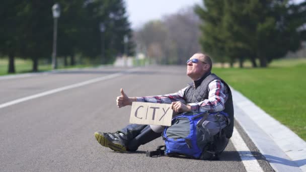  Pozitív felnőtt ember autóstoppal autó üres úton.. Poszterváros - Felvétel, videó