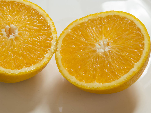 Primo piano di due metà di arancia succosa affettata, su sfondo bianco con ombre
. - Foto, immagini