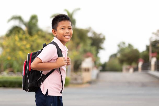 Щасливий азіатський школяр в уніформі з рюкзаком, що йде додому
. - Фото, зображення