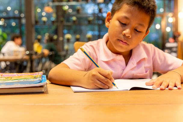 Aziatische scholier hand met potlood doet zijn huiswerk thuis. - Foto, afbeelding