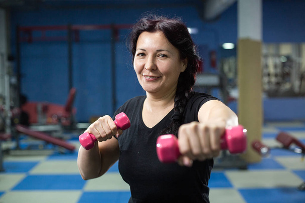 Senior woman in gym working out with dumbbells. close-up. copy space. - Foto, Imagem