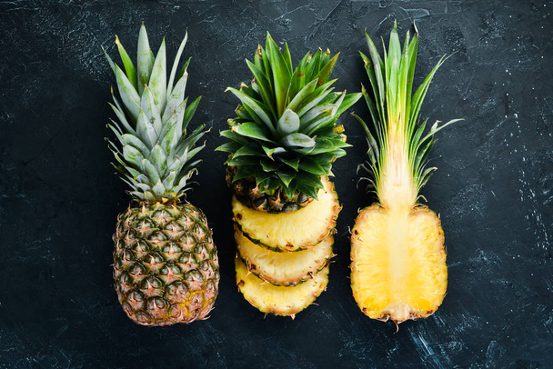 Sliced pineapple on a black background. Tropical Fruits. Top view. Free copy space. - Zdjęcie, obraz