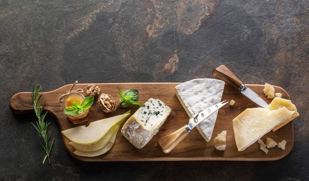 Cheese platter with organic cheeses, fruits and nuts on stone ba - Foto, afbeelding