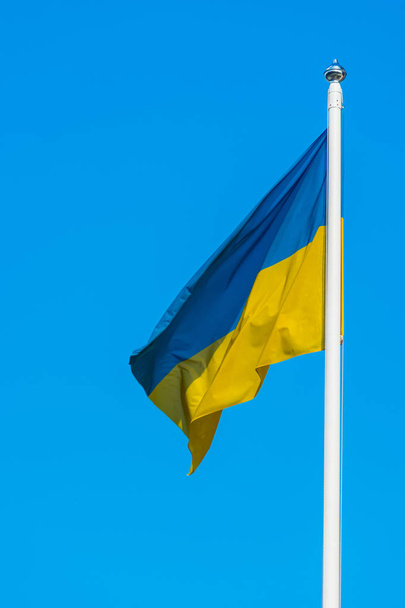 Foto di una bandiera dell'Ucraina sono ondeggianti nel vento su pennone su uno sfondo di cielo blu chiaro
 - Foto, immagini