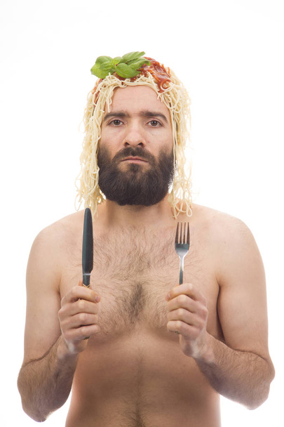Szakállas, vicces, fiatal férfi spagetti a fején. Evőeszközök. Fehér háttér. Ruházat nélküli testápoló. Portré fotó. Kaukázusi fickó. - Fotó, kép