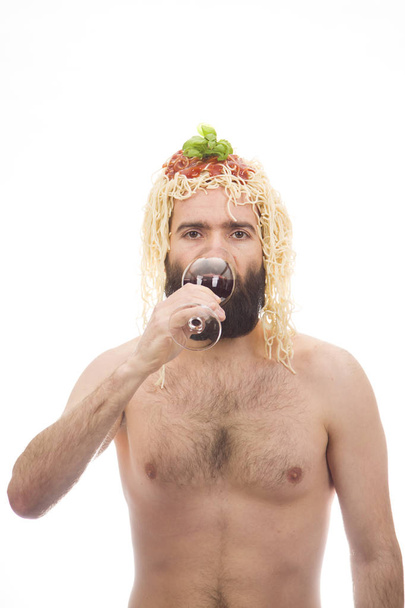 Bearded, funny, young man with spaghetti on his head. Drinking wine. Glass. White background. Body without clothing. Portrait photo. Caucasian guy. - Photo, Image