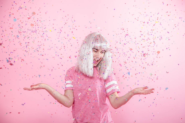 Funny Girl with silver hair gives a smile and emotion on pink background. Young woman or teen girl with confetti - Zdjęcie, obraz