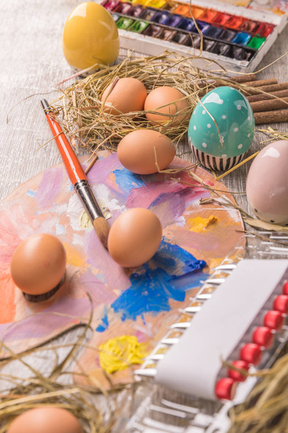 Young woman painting Easter eggs, white covered table.Preparation for happy Easter holiday.Woman hands painting decorative colorful eggs, handmade Easter craft top view - Fotó, kép