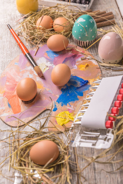 Young woman painting Easter eggs, white covered table.Preparation for happy Easter holiday.Woman hands painting decorative colorful eggs, handmade Easter craft top view - Foto, Imagem