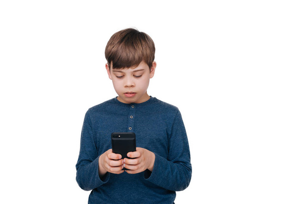 Photo of little boy using a smartphone, standing over white wall backgound  - Photo, image