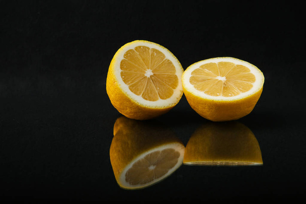 two halves of lemon on a black background close up with reflection. citrus fruit isolated  on black background - Foto, Imagen