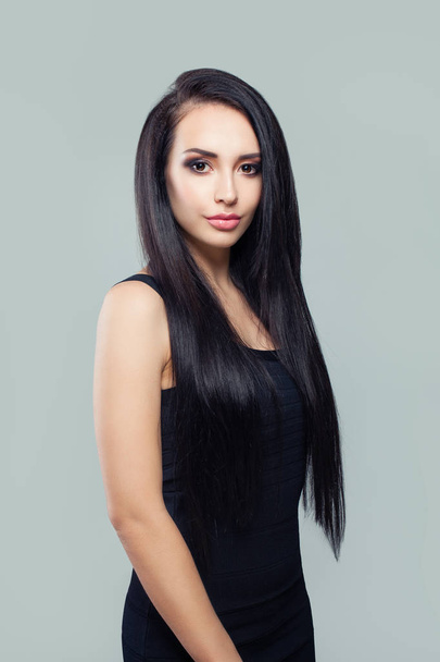 elegante Frau mit langen gesunden glatten Haaren und Make-up in schwarzem Kleid - Foto, Bild