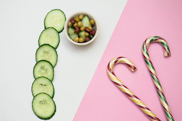 sliced fresh cucumber salad and candy pink on a white background - Фото, изображение