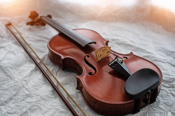 The wooden violin and bow put on grunge surface background,warm light tone,blurry light around. - Photo, Image
