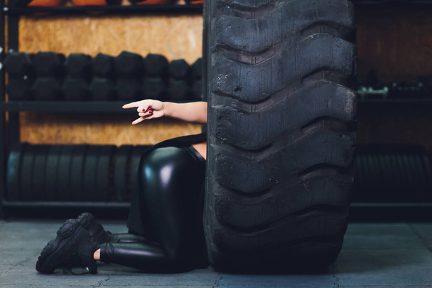 Fit female athlete working out with a huge tire, turning and carry in the gym. woman exercising with big tire. - Valokuva, kuva