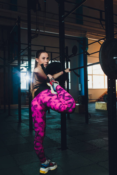 a beautiful sports girl trains a bicep with a rod in her hands in the gym. - Zdjęcie, obraz