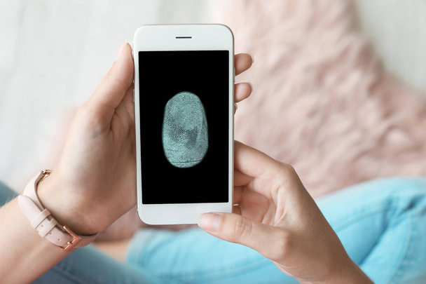 Žena, která drží mobilní telefon se snímačem prstů, zaostřená - Fotografie, Obrázek
