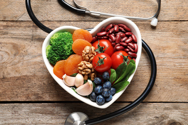 Bowl with products for heart-healthy diet and stethoscope on wooden background, top view - Foto, Imagen