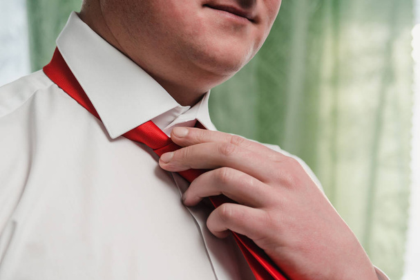Un homme en chemise blanche noue une cravate rouge autour de son cou tout près
 - Photo, image