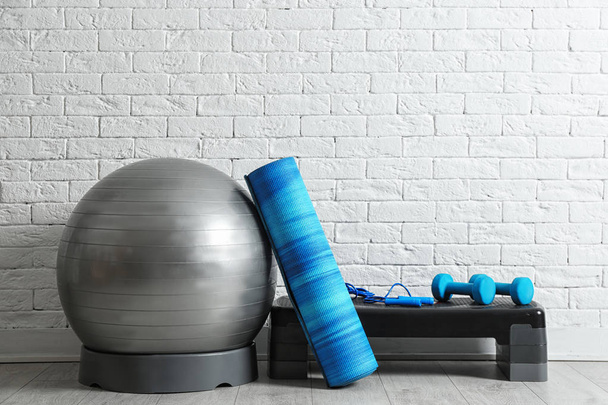 Set of fitness inventory on floor near brick wall. Space for text - Fotoğraf, Görsel