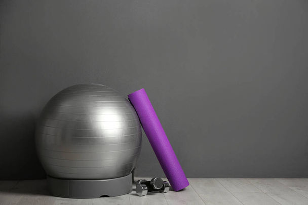 Set of fitness inventory on floor near grey wall. Space for text - Фото, изображение