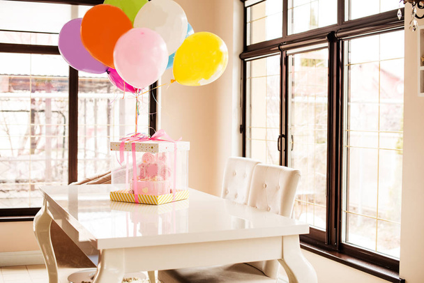 vaaleanpunainen kakku tytön ensimmäisen syntymäpäivän, ilmapallojen ja onnittelujen kunniaksi, 1 vuosi
 - Valokuva, kuva