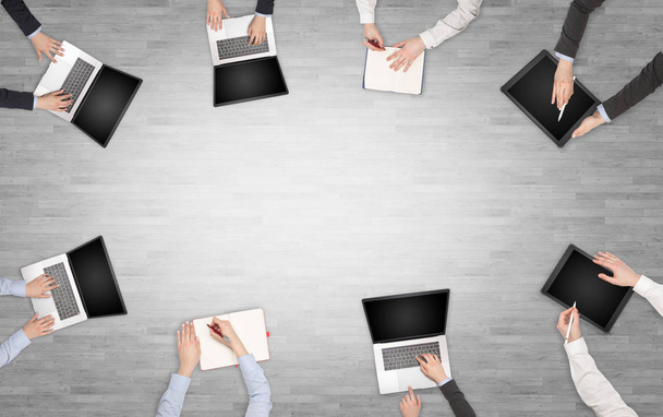 Группа людей с устройствами в руках, занимающихся настольным обсуждением и работой с ноутбуками, планшетами в команде
 - Фото, изображение
