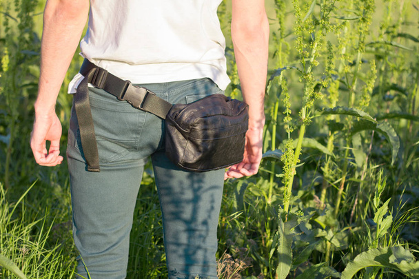 Young male traveler with belt bag stand in the fields against city - Photo, Image