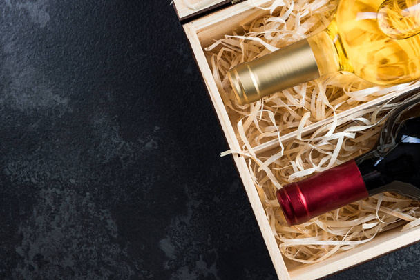 Red and white wine bottles in wooden crate - Photo, Image