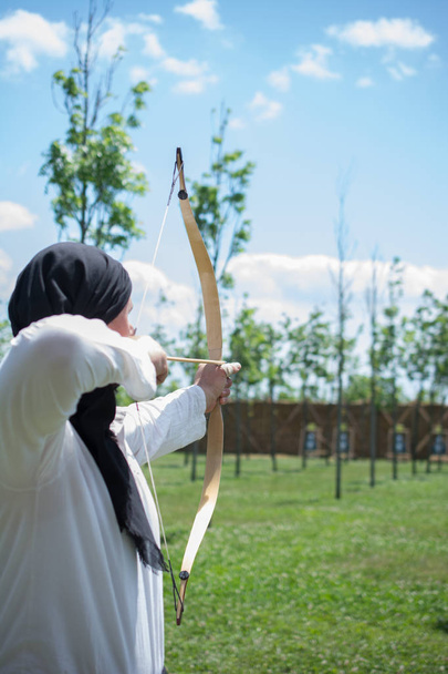 Archer en ropa tradicional disparando una flecha
 - Foto, Imagen