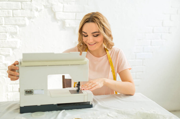 縫製機の近くのテーブルで仕事で美しい若い女の子のお針子デザイナー - 写真・画像