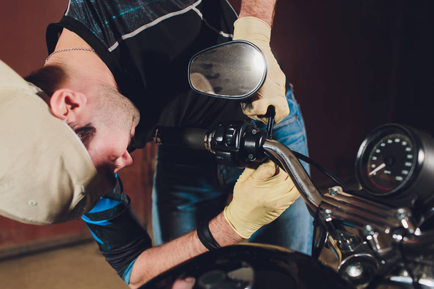 Man fixing bike. Confident young man repairing motorcycle near his garage. rearview mirror adjustment. - Fotoğraf, Görsel