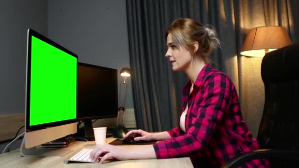 La mujer trabaja en su computadora, trabaja en la oficina. Monitor de pantalla verde, vista lateral
. - Metraje, vídeo