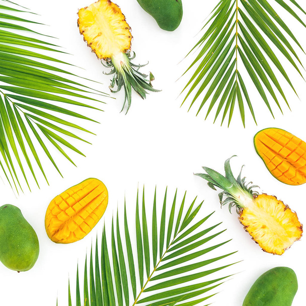 Tropic pattern of pineapple and mango fruits with palm leaves on white background. Flat lay, top view - Photo, Image