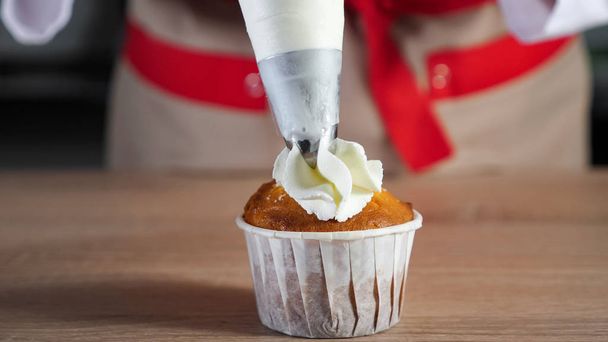 Cukrářské šéfové zdobí Muffin v papírové šálky s cukráčkem. - Fotografie, Obrázek