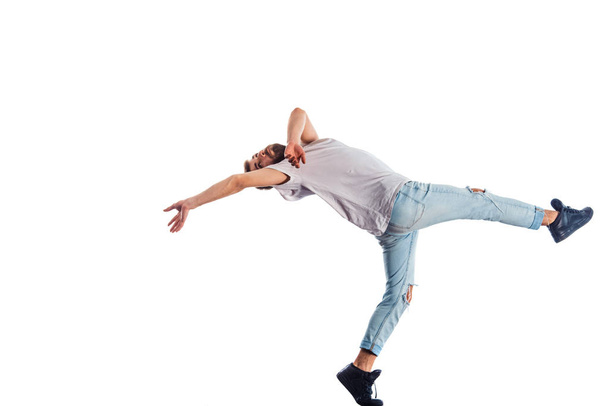 Cool man is showing gymnastics moves in isolated white room - Photo, Image
