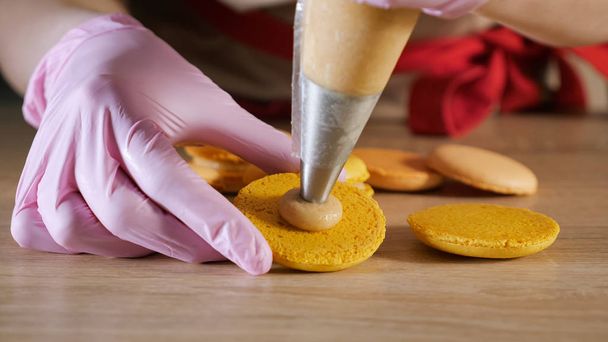chef de pastelaria está enchendo macaroons de limão com creme usando saco de confeitaria
. - Foto, Imagem