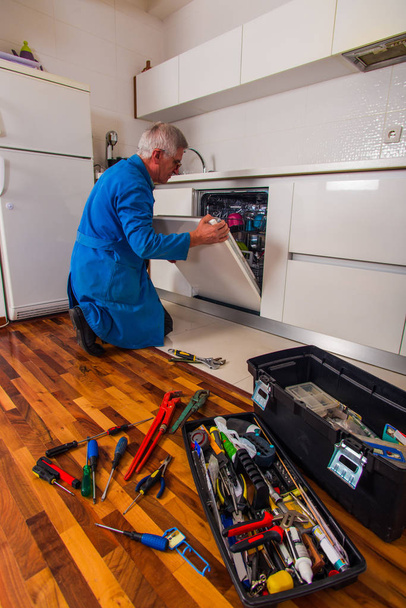 Profesyonel işçi mutfakta bulaşık makinesini tamir ediyor - Fotoğraf, Görsel