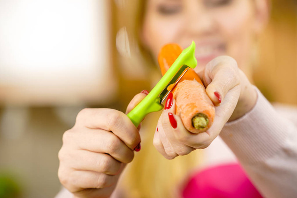 Woman peeling carrot vegetable - Foto, afbeelding